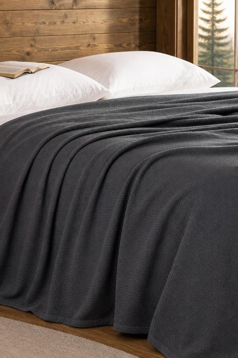 Dark charcoal gray diamond-weave cooling blanket draped over a bed in a cabin bedroom with a book on the pillow