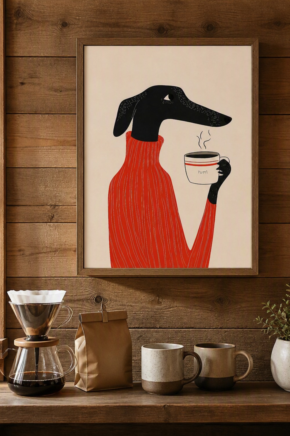 Framed minimalist illustration of a black greyhound in a red sweater sipping coffee, hung above a small coffee bar in a cabin