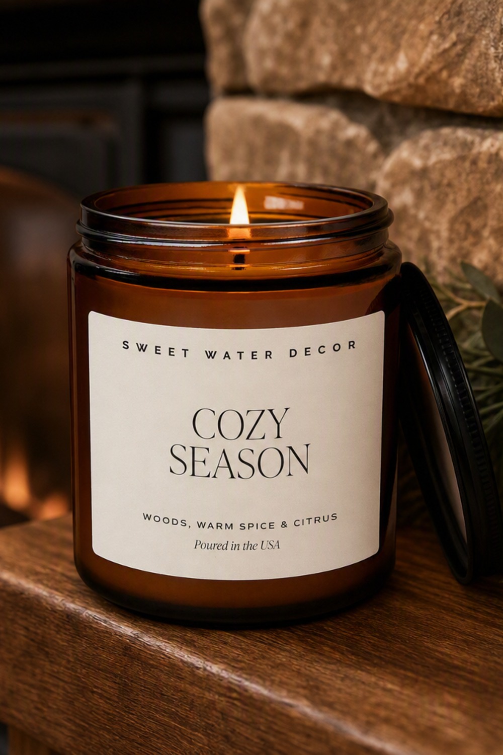 Sweet Water Decor Cozy Season amber jar candle lit on a mantel by the fireplace
