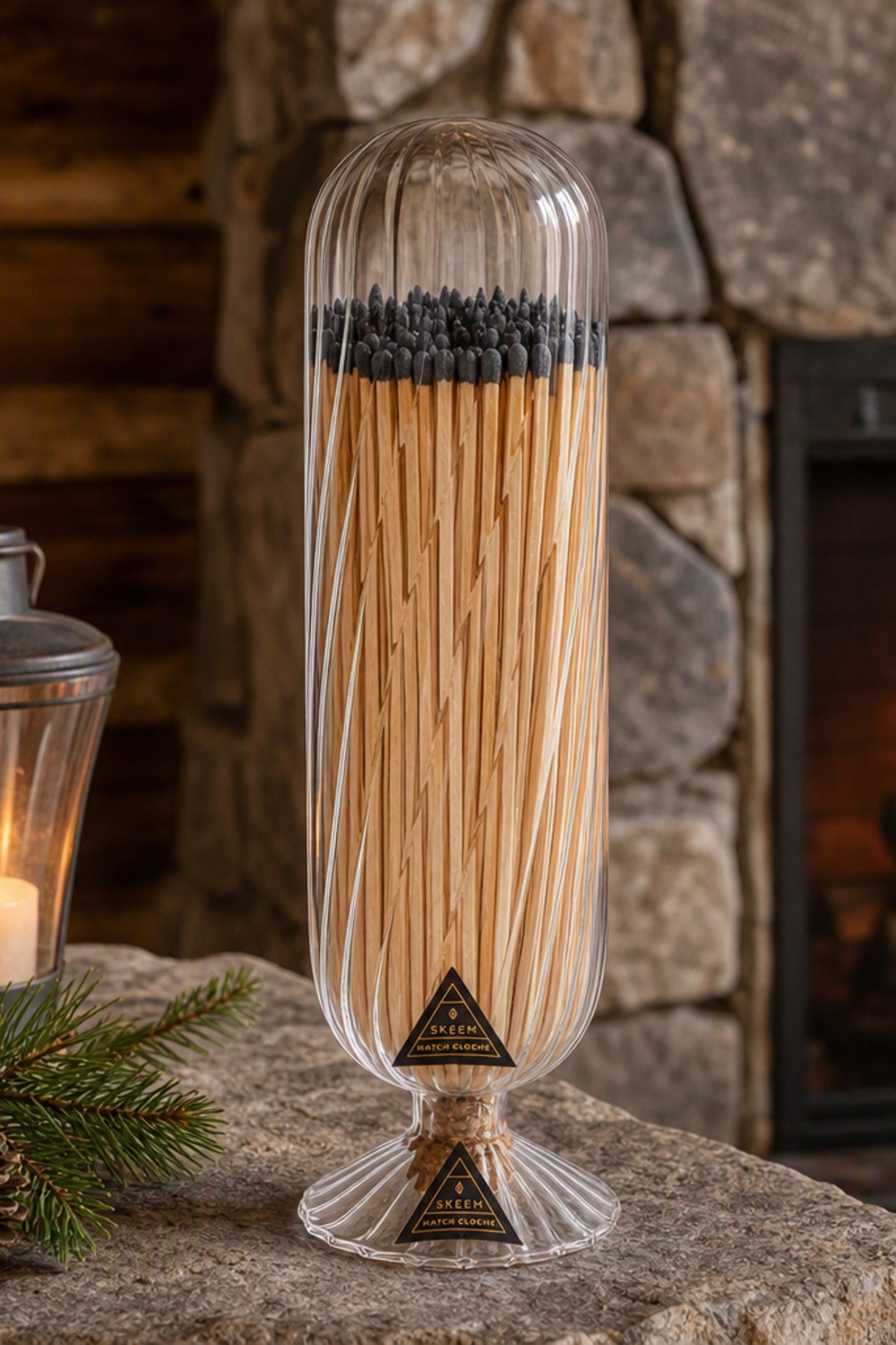 Skeem Helix glass match cloche packed with long black-tipped matches on a stone fireplace mantel