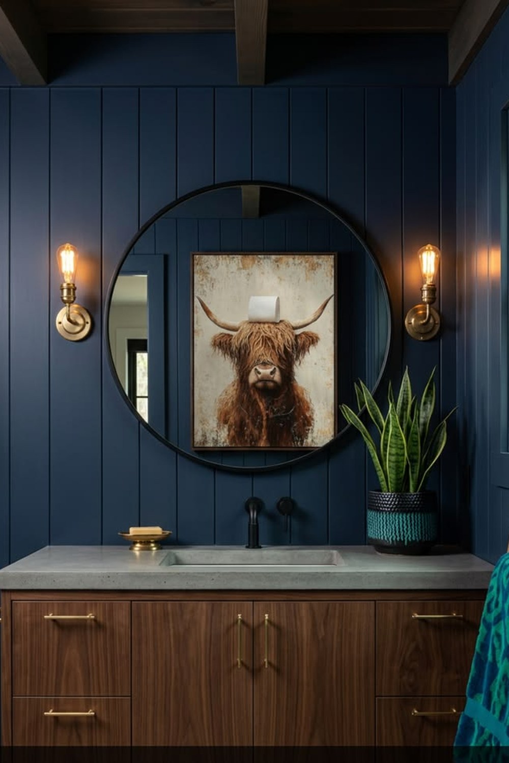Funny framed Highland cow bathroom print on a navy plank wall over a walnut vanity in a cabin bathroom