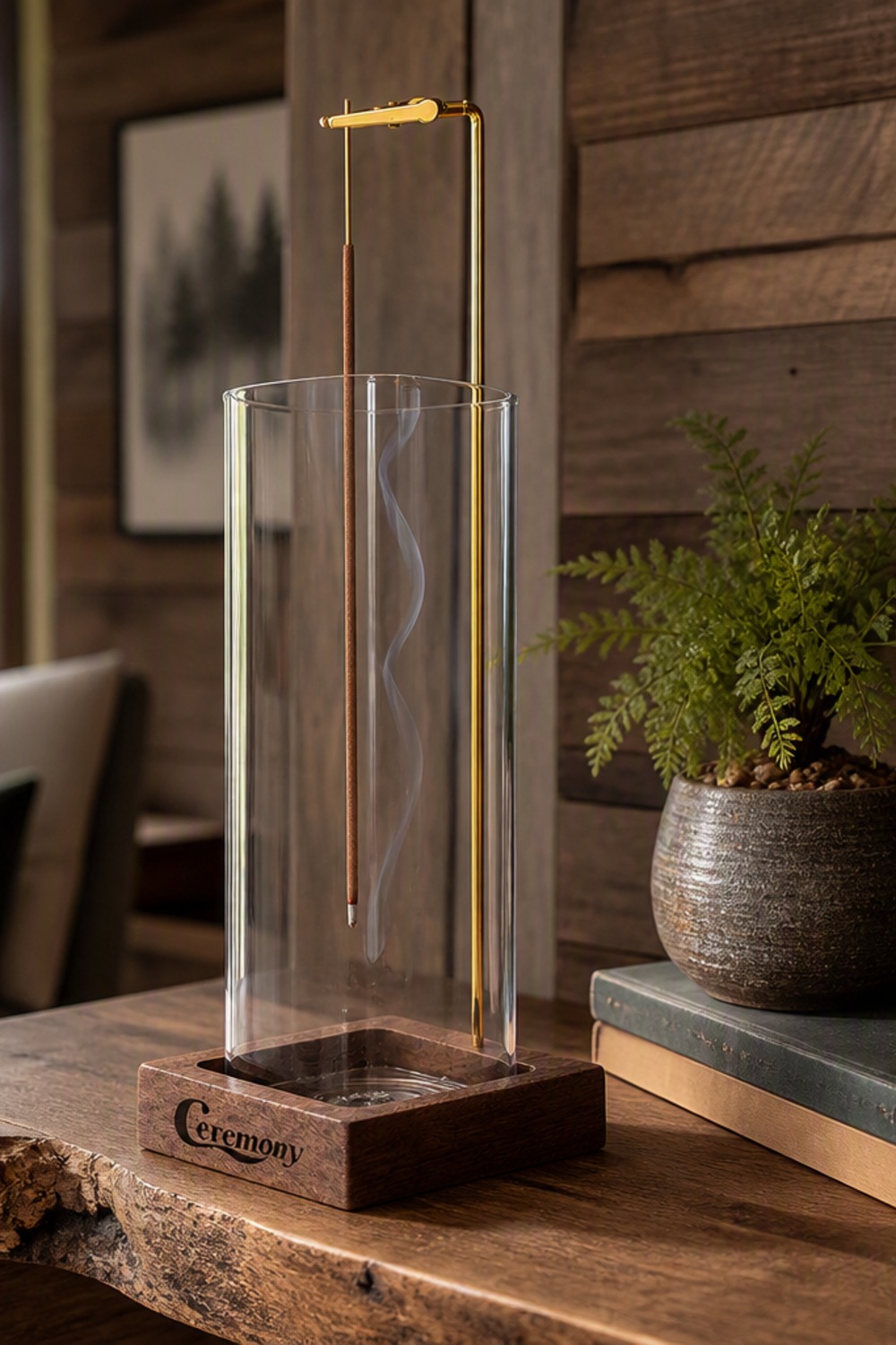 Backflow incense holder with a glass cylinder, gold arm, and walnut base on a cabin console table