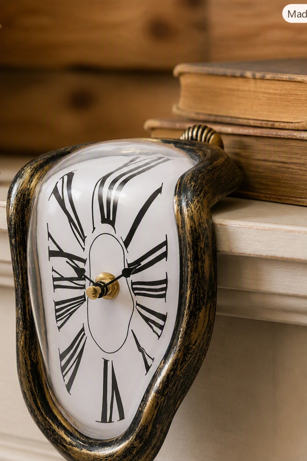 Surreal Salvador Dali-style melting shelf clock in distressed matte black and gold, draped over a wood mantel shelf edge in a cabin living room