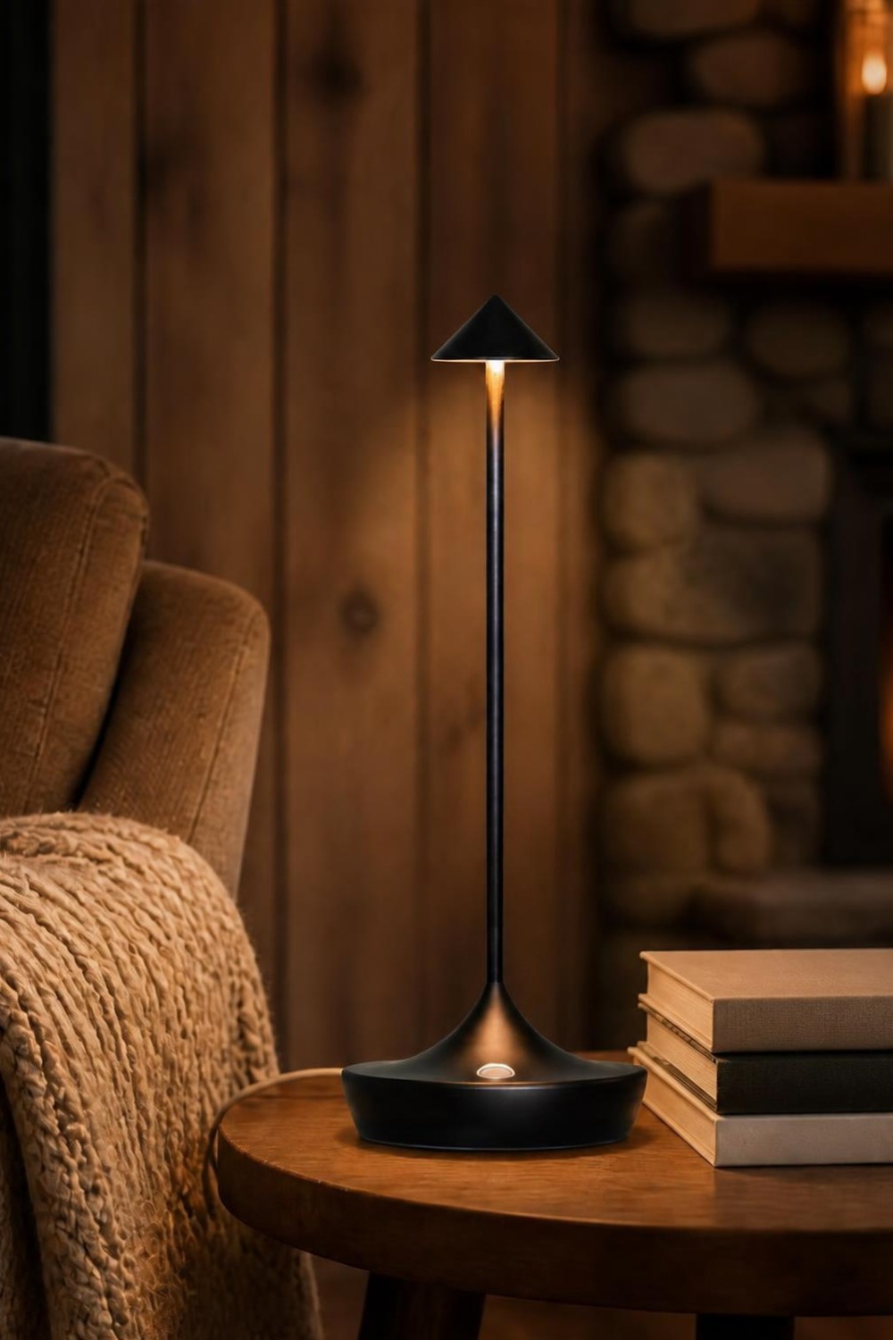 Matte black minimalist cordless table lamp with a cone shade on a side table in a cabin living room