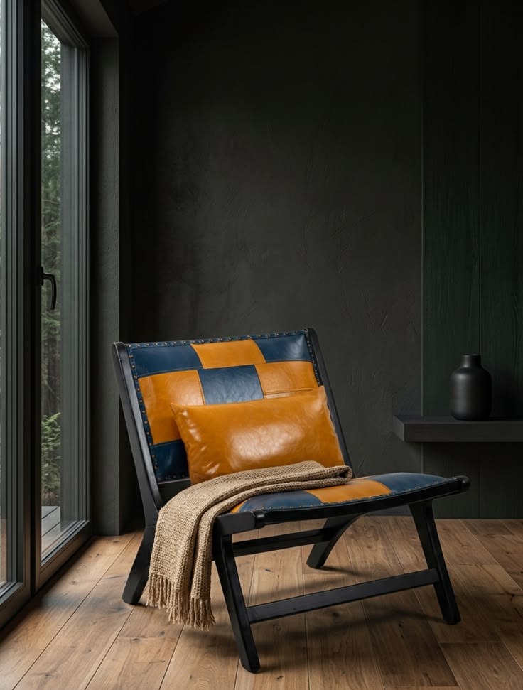 Caramel and navy patchwork genuine-leather accent chair with a matching lumbar pillow in a moody dark-green cabin corner
